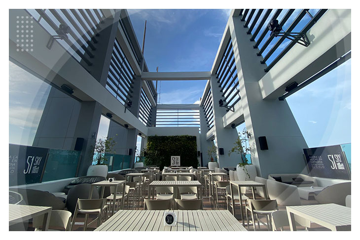 Terraza con mesas y sillas claras, cielo azul despejado, un ambiente fresco y elegante, hace parte de la experiencia que ofrecen los mejores hoteles en Cartagena