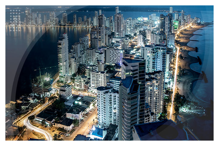Vista de la ciudad de Cartagena al anochecer con edificios altos, calles iluminadas y el mar de fondo, ideal para quienes buscan habitaciones todo incluido en el Hotel Estelar y centro de convenciones