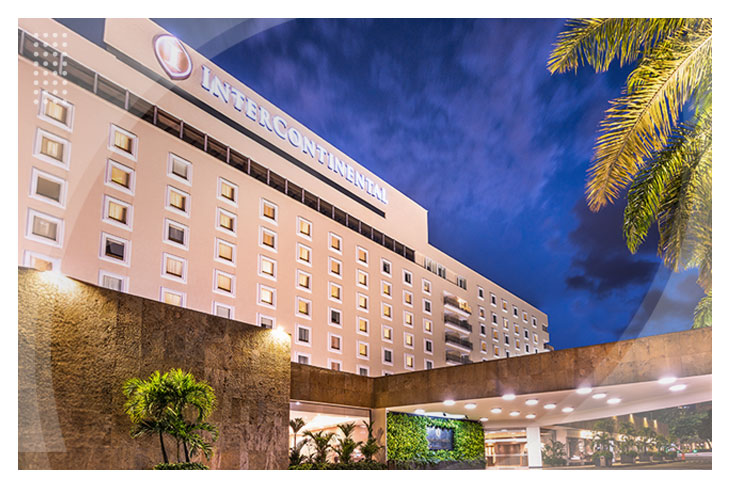 Hoteles Estelar en Cali con descuento como el Intercontinental destacan por su fachada moderna, rodeada de palmeras y una vista despejada del cielo al atardecer