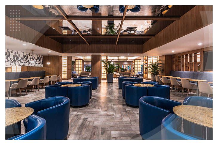 Salón moderno con sillones azules, mesas redondas y una atmósfera sofisticada que representa el estilo exclusivo del hotel Estelar Intercontinental