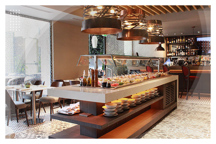 Zona de buffet gourmet con amplia variedad gastronómica, lámparas colgantes e iluminación cálida en un espacio moderno del Hotel Intercontinental, uno de los mejores hoteles en Cali