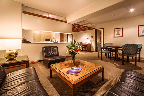 Gran habitación que tiene sala, comedor, cocina y espacios amplios, iluminados por lámparas y luces cálidas que se pueden encontrar con los descuentos en reserva de apartamentos Estelar Perú