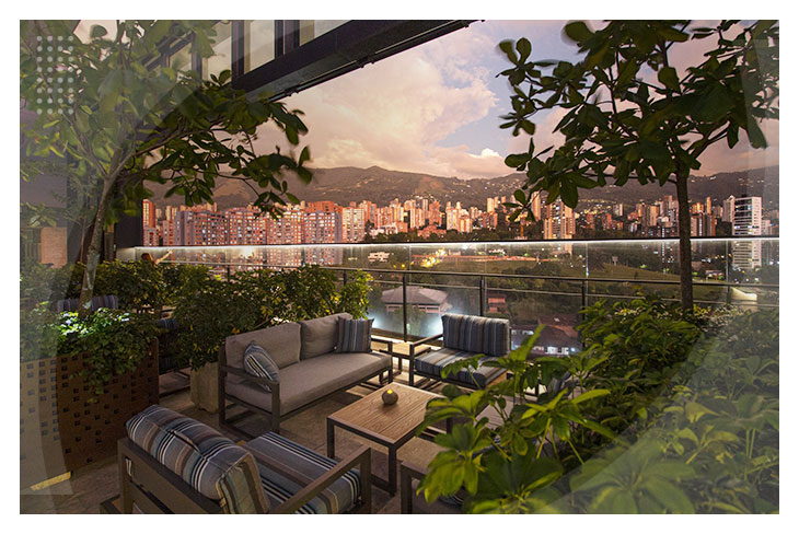 Terraza con vista panorámica al atardecer, con cómodos muebles de exterior, ideal para relajarte en el mejor hotel en Medellín con rooftop