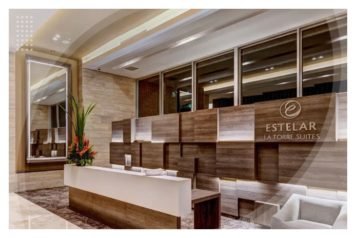 Recepción con acabados en madera y mármol, que refleja el estilo sofisticado que ofrecen los descuentos en el Hotel Estelar la Torre Suites, acompañada de iluminación cálida y detalles decorativos elegantes