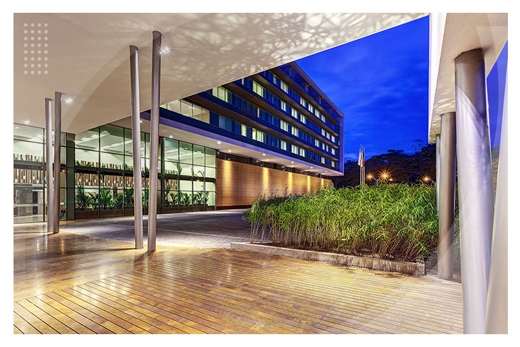 Fachada de un hotel con iluminación nocturna, rodeada de jardines y pisos de madera que dan la bienvenida a quienes buscan hoteles en Villavicencio con descuento