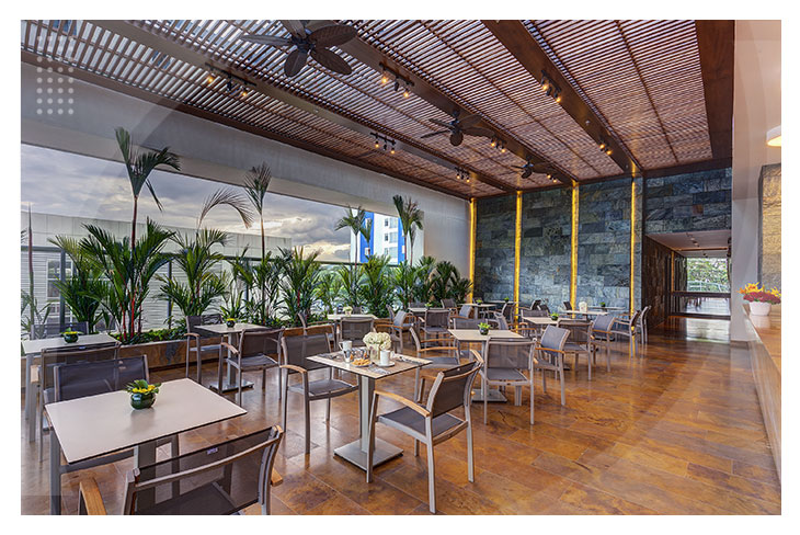 Restaurante con techo de madera, mesas, sillas y plantas decorativas que crean un ambiente acogedor ideal para disfrutar una comida en hoteles cerca del Parque Los Fundadores