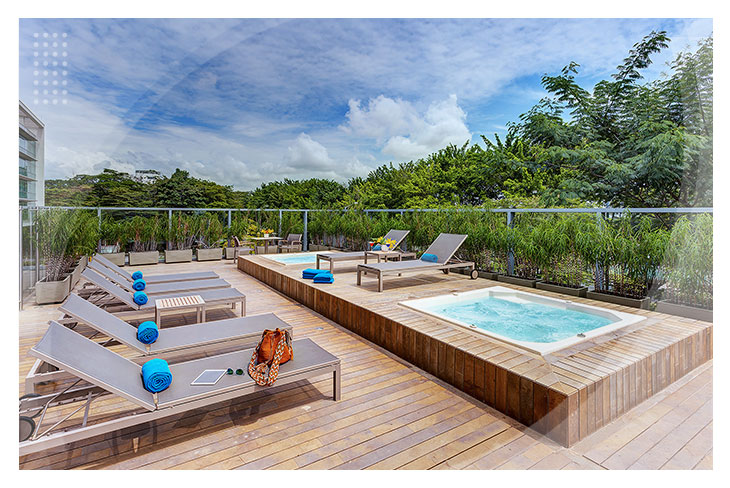Zona de descanso al aire libre con jacuzzi rodeado de sillas asoleadoras, toallas azules y naturaleza que invitan al descanso en habitaciones con descuento en Villavicencio
