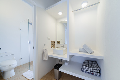 Baño de las habitaciones con descuento del hotel Las Palmeras con un lavamanos con espejos, closet e inodoro blancos