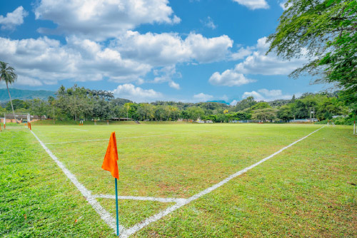 Cancha de fútbol de las instalaciones del hotel Las Palmeras, con una bandera naranja y unas líneas blancas de limitación del campo