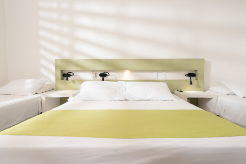 Habitación de Las Palmeras en Villeta perteneciente al plan básico para niños de 2 a 11 años, que cuenta con dos camas sencillas, un televisor, un ventilador y una ventana grande