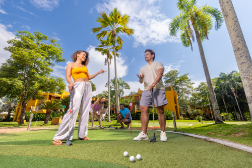 Una mujer y un hombre, que usan ropa cómoda, juegan golfito en una de las canchas que están rodeadas de naturaleza y a las cuales se puede acceder luego de hacer una reserva en el hotel Lagosol