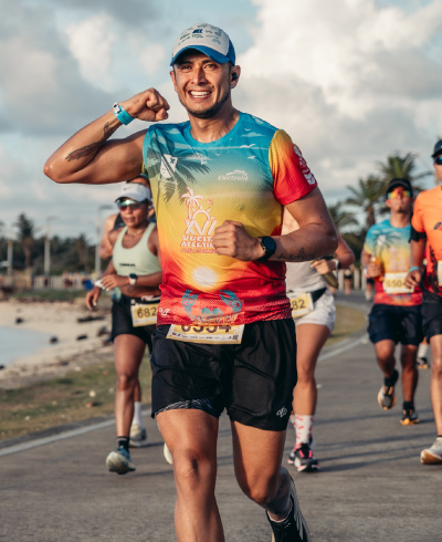 Corredores, vestidos con ropa para running, trotan junto a la playa durante la vuelta atlética a San Andrés, celebrando su llegada a la meta
