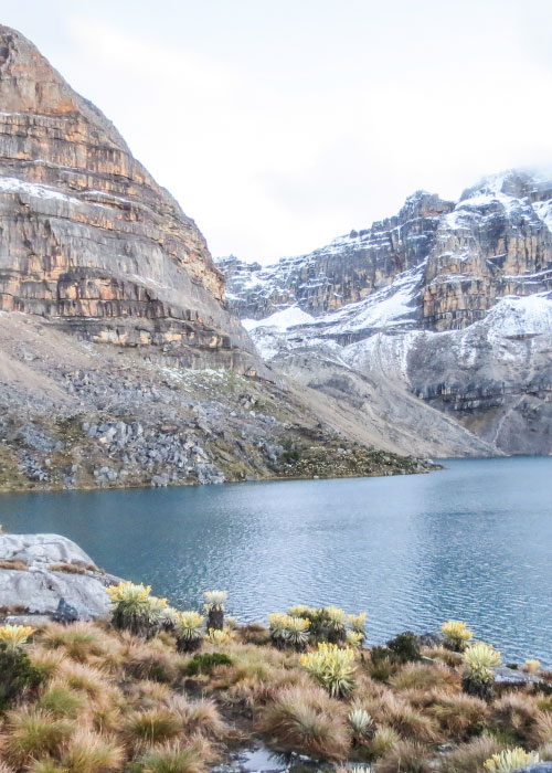 Vista panorámica de la Laguna Grande, ubicada en el municipio de Güicán Boyacá, en donde se puede ver vegetación de la zona y una gran montaña con nieve, la cual se puede conocer luego de comprar los paquetes turísticos de la agencia de viajes Compensar